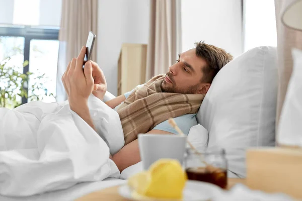 人々の概念 自宅でベッドでスマートフォンを持つ病人 — ストック写真