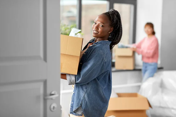 moving, people and real estate concept - happy smiling women with boxes at new home