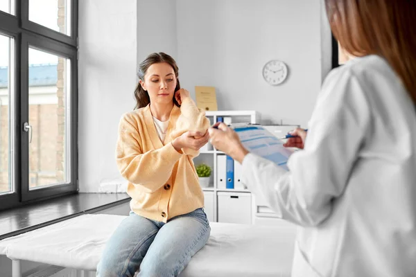 医疗保健和人的概念 在医院与显示手臂酸痛病人的妇女交谈的女医生 — 图库照片