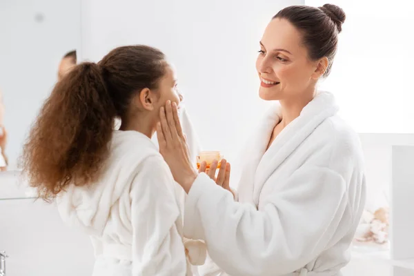 朝と人々のコンセプト バスルームで保湿剤と幸せな笑顔の母親と娘 — ストック写真