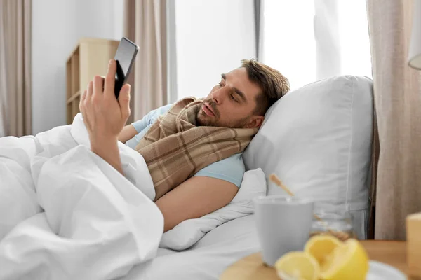 Saúde Doença Conceito Pessoas Homem Doente Com Smartphone Cama Casa — Fotografia de Stock