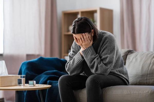 mental health, psychological problem and depression concept - stressed woman with sedative medicine or painkiller on table having headache at home