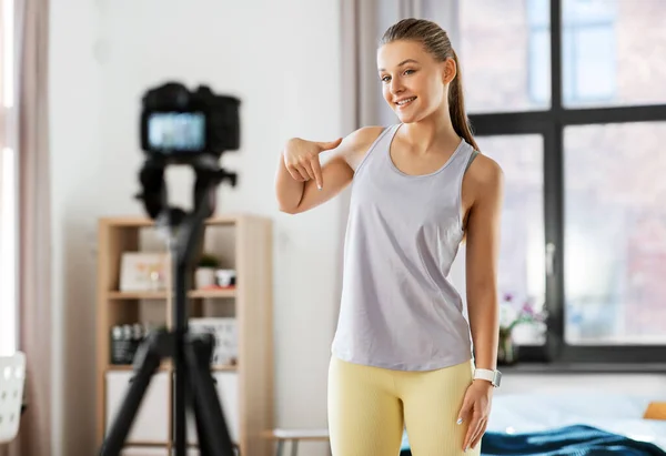 fitness, sport and video blogging concept - happy smiling teenage girl or blogger with camera on tripod recording online gym class at home