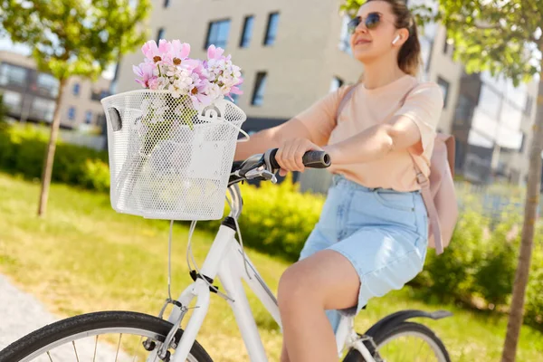 stock image people, leisure and lifestyle - close up of happy smiling woman with earphones, backpack and flowers in basket riding bicycle on city street