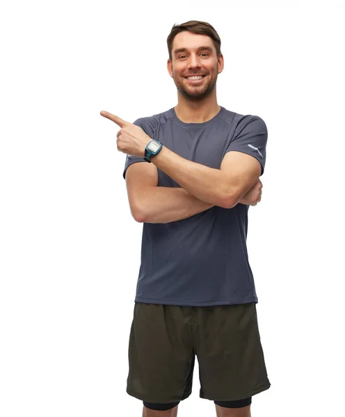 フィットネス スポーツ 健康的なライフスタイルのコンセプト 白い背景に見えない何かを示すスマートウォッチやトラッカーとスポーツ服の笑顔の男 — ストック写真