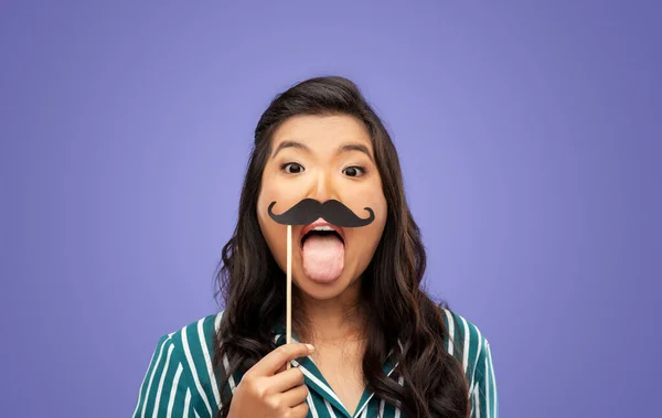 party props, photo booth and people concept - happy woman with big black moustaches sticking out her tongue over violet background