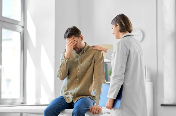 医疗保健和人的概念 有剪贴板的女医生和在医院有健康问题的悲伤男性患者 — 图库照片
