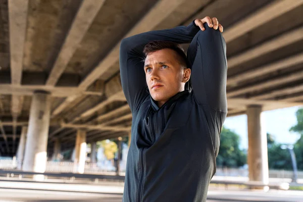 フィットネス スポーツ 健康的なライフスタイルのコンセプト 橋の下で肩を伸ばす男 — ストック写真