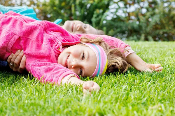 Glad liten flicka liggande på gräs — Stockfoto