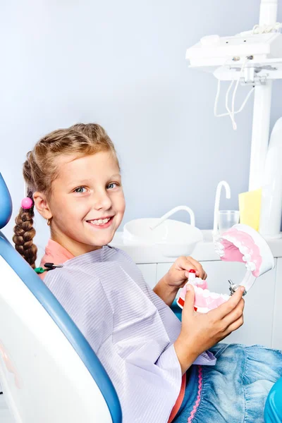 Girl cleaning toy dentures — Stock Photo, Image