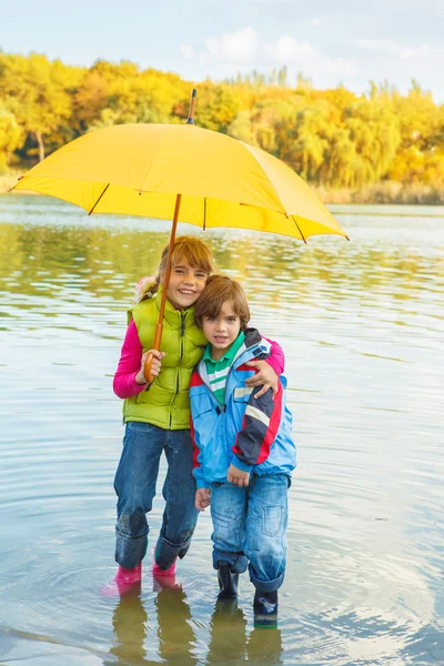 Lovely siblings under umbrella — Stockfoto