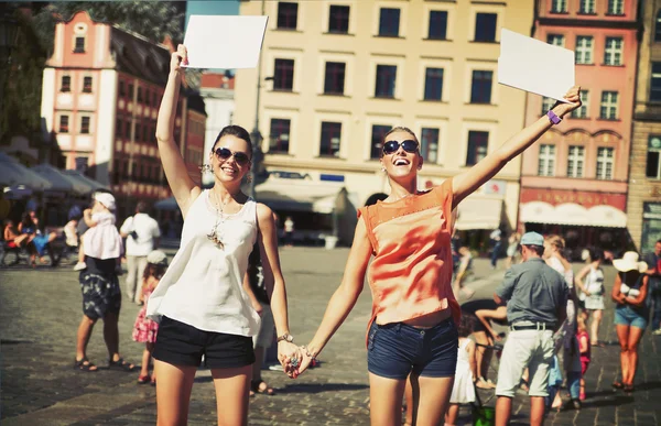 Две улыбающиеся девушки держатся за доску — стоковое фото