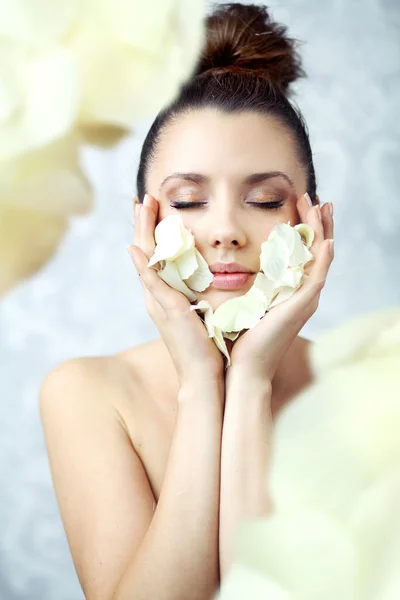 Pretty brunette holding petals close to face — Stock Photo, Image