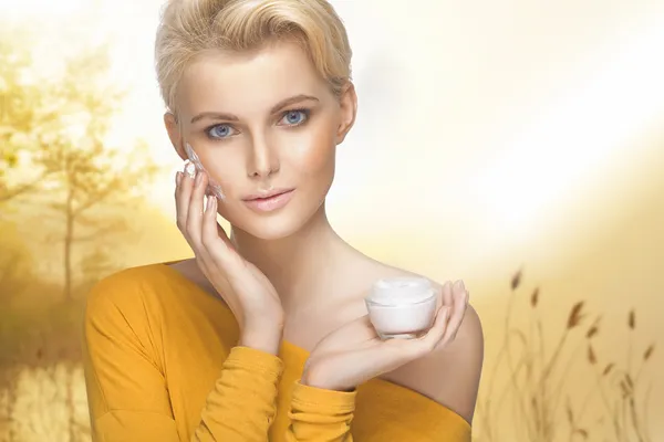 Porträt einer jungen Frau, die Feuchtigkeitscreme auf ihr hübsches Gesicht aufträgt — Stockfoto