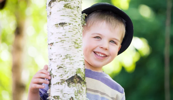 Cheerful boy hiding himself in the garden — Stock Photo, Image