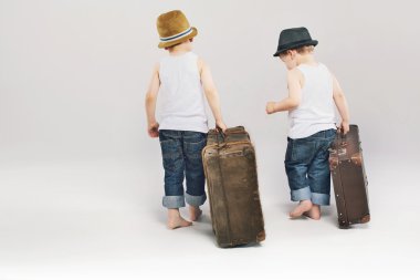 Two cute brothers leaving with their suitcases clipart