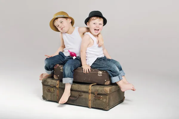 Dois irmãos pequenos sentados nas malas — Fotografia de Stock