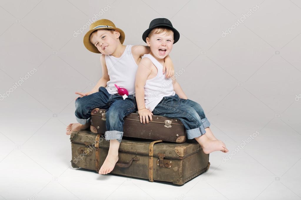 Two small brothers sitting on the suitcases