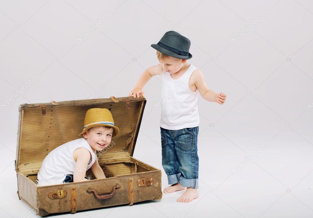 Small boy hiding his elder brother in suitcase