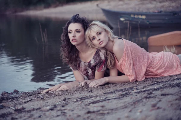 Zwei Freundinnen, die sich am Strand hinlegen — Stockfoto