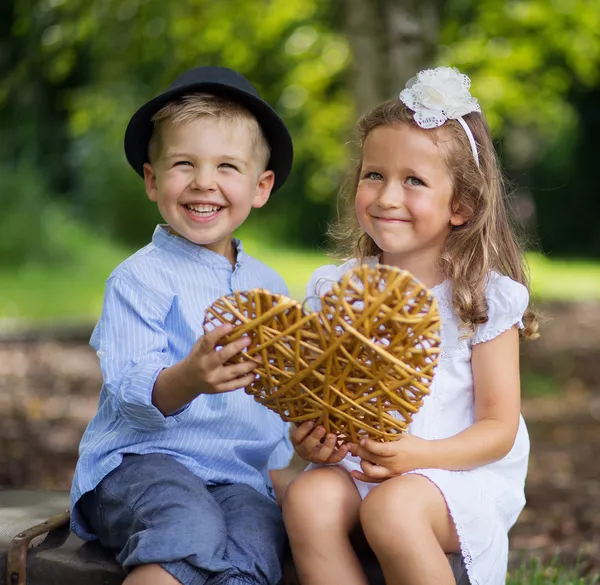 Två skrattande barn hålla wicker hjärta — Stockfoto