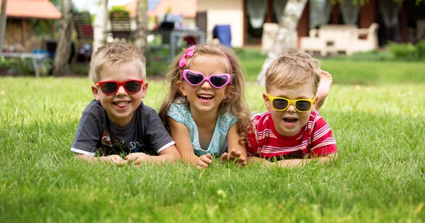 Feliz risa niños acostados en la hierba — Foto de Stock