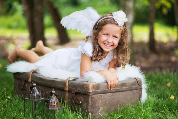 Μικρό χαριτωμένο Άγγελος στηρίζεται σε βαλίτσα Εικόνα Αρχείου
