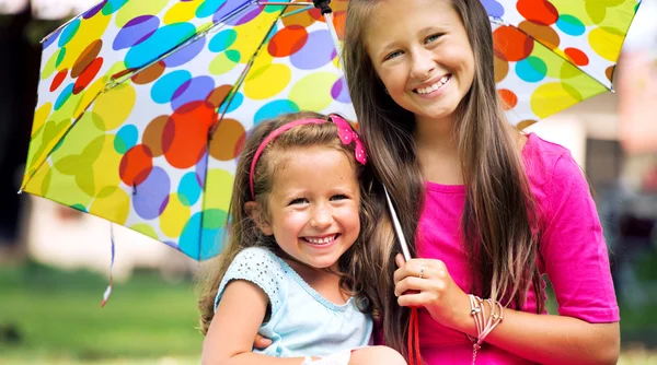 Young sisters posing with colorful umbrella — Stock Photo, Image