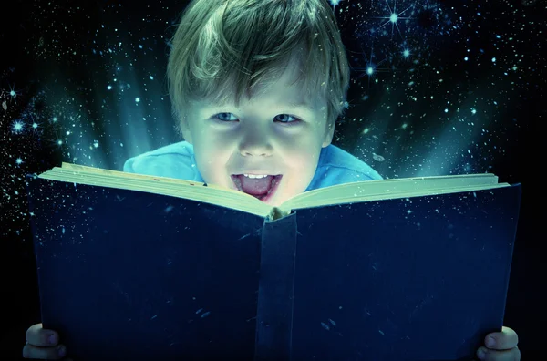 Śmiejąc się mały chłopiec z magiczna książka — Zdjęcie stockowe