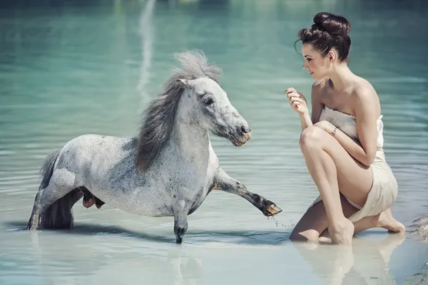 Заманчивая женщина играет с пони в бассейне — стоковое фото