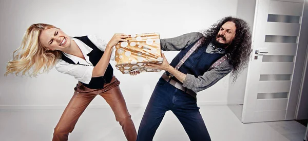 Jeune Couple Bizarre Sur Fond Blanc Posant Avec Cadeau Noël Image En Vente