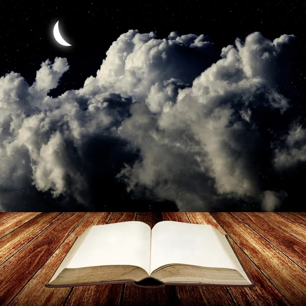 Open blak book on wooden table with night sk — Stock Photo, Image