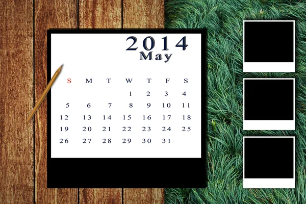 Calendario 2014 impostato con cornice fotografica su pavimento in legno e sfondo erba — Foto Stock