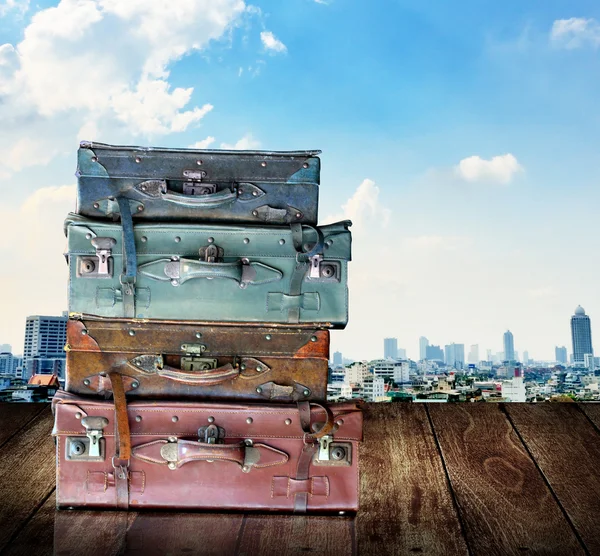 Bagagli da viaggio vintage su parete di legno con sfondo vista città — Foto Stock