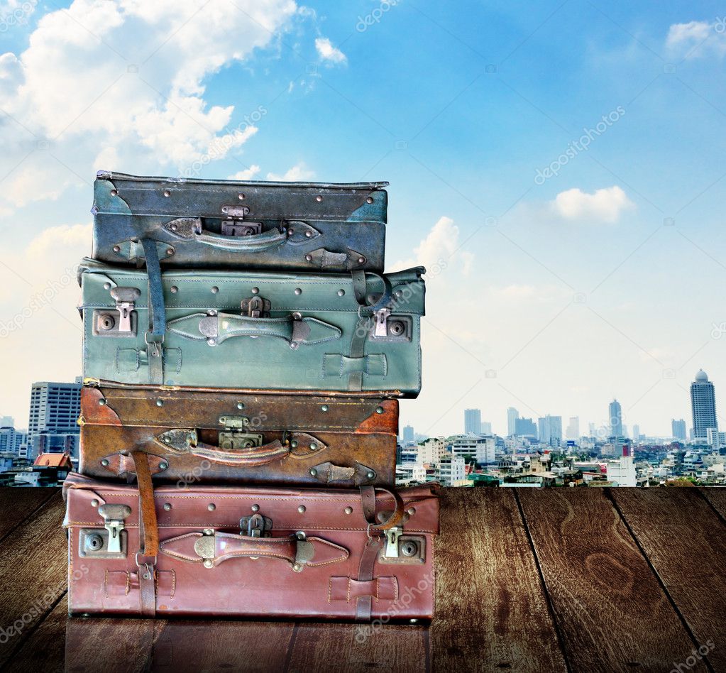 Vintage travel luggage on wooden wall with city view background