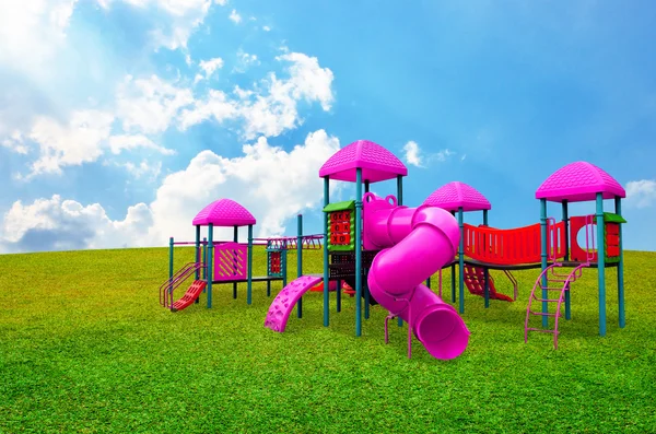 Crianças coloridas s playground no jardim com fundo agradável céu — Fotografia de Stock