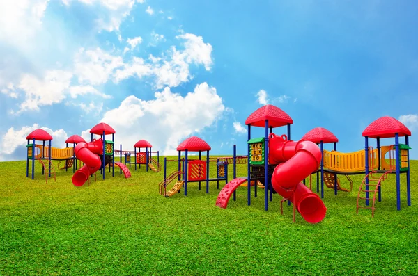 Красочная детская игровая площадка в саду на красивом фоне неба — стоковое фото