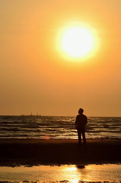Sylwetka człowieka na plaży, w tle niebo zachód słońca — Zdjęcie stockowe