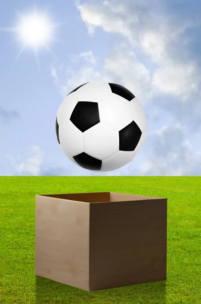 Football in open box with field background — Stock Photo, Image