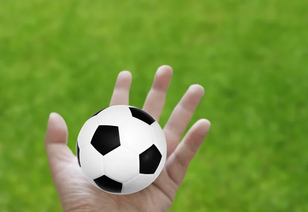 Voetbal in de hand met gras achtergrond — Stockfoto