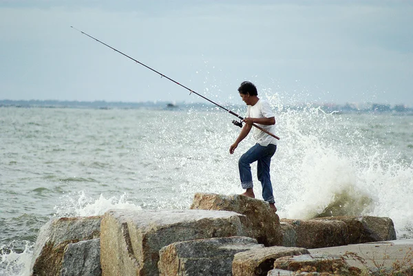 CHONBURI, THAILAND - JULY 25 : Unidentified man fishing with big wave splashing on 15 April 2011 in Sriracha beach, Chonburi, Thailand — Stock Photo, Image