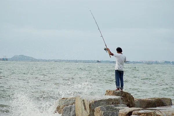 CHONBURI, THAILAND - JULY 25 : Unidentified man fishing with big wave splashing on 15 April 2011 in Sriracha beach, Chonburi, Thailand — Stock Photo, Image