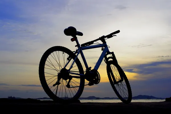 Silhouette of mountain bike with sunset sky and island — Stock Photo, Image