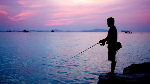 Silhouette of fishing man beside the sea — Stock Photo, Image