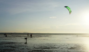 CHONBURI, THAILAND - 26 Mart 2022 'de BangSaen, Chonburi, Tayland' da günbatımı arka planıyla denizde uçurtma sörfü