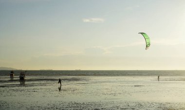 CHONBURI, THAILAND - 26 Mart 2022 'de BangSaen, Chonburi, Tayland' da günbatımı arka planıyla denizde uçurtma sörfü