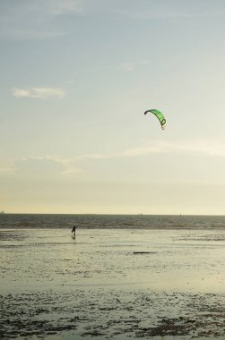 CHONBURI, THAILAND - 26 Mart 2022 'de BangSaen, Chonburi, Tayland' da günbatımı arka planıyla denizde uçurtma sörfü