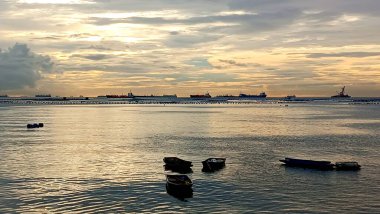 Silhouette of small boat at sea with cargo ship background