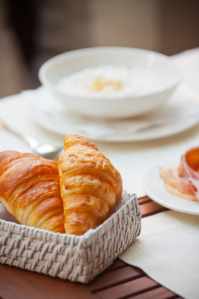 Snídaně s kávou a croissanty v košíku na stole — Stock fotografie