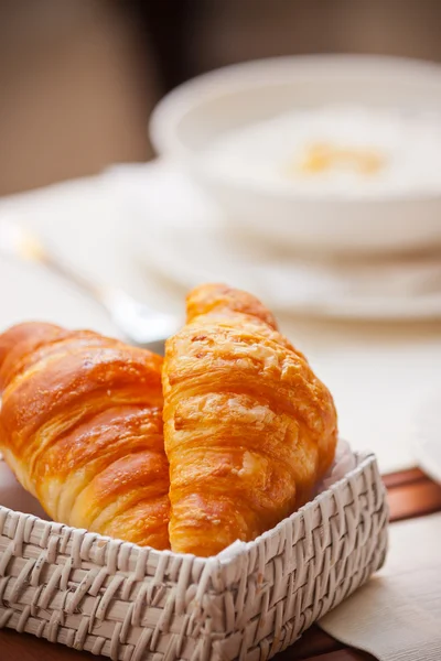 Snídaně s kávou a croissanty v košíku na stole — Stock fotografie